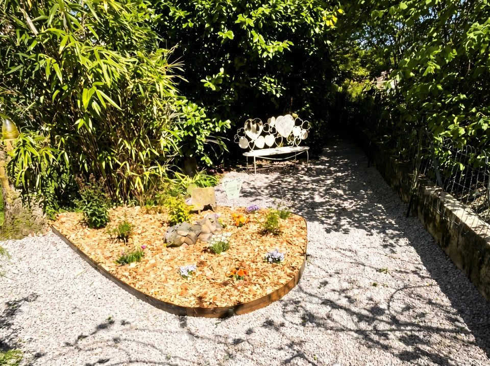 Paysage extérieur d'une maison montrant à la fois des éléments d'aménagement paysager et de maçonnerie : au premier plan une terrasse pavée ou dallée récemment construite, flanquée de massifs de plantes bien entretenus, d'arbustes taillés et de pelouse verte. L'arrière-plan peut inclure une clôture en aluminium ou un portail. La scène doit montrer clairement les deux domaines de compétence : espaces verts d'un côté et structures maçonnées de l'autre, illustrant ainsi le double savoir-faire de l'entreprise.